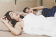 snoring woman, Asian Girls can not sleep, covering ears with Hands for snore noise, sleeping in bedroom. Woman suffers from her female partner or friend snoring in bed. with Copy space. horizontal