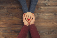 Man Holding Woman's Hands Top View Image On Dark Wooden Backdrop. Couple In Love Consept.	