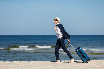 Wall Mural - Businessman carrying suitcase on beach 