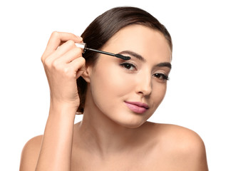 Wall Mural - Beautiful young woman with eyelash extensions applying mascara, on white background