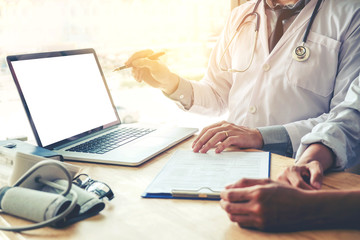 Wall Mural - Doctor consulting with patient presenting results on blank Screen tablet computer sitting at table