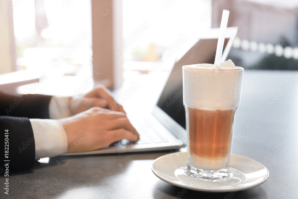 Young man using laptop at table in cafe