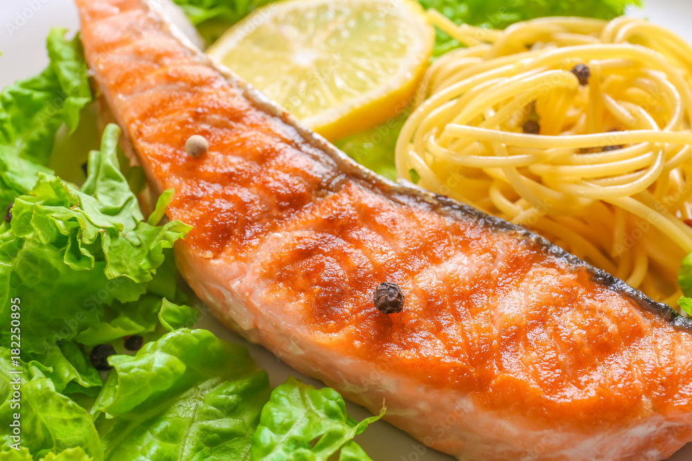 Tasty grilled salmon and pasta on plate, closeup