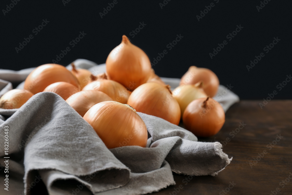 Fresh raw yellow onion on fabric and wooden background