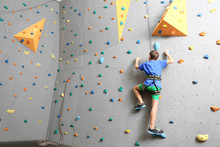 Young Boy Climbing Wall In Gym