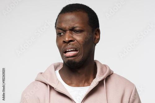 Dégoûtant! Choqué jeune homme afro-américain en regardant quelque chose de désagréable et mauvais, isolé sur fond gris Poster Mural XXL