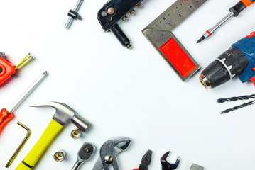 Top view of Working tools,wrench,socket wrench,hammer,screwdriver,plier,electric drill,tape measure,machinist square and safety glasses on white background.flat lay design