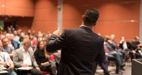 Speaker giving a talk on corporate Business Conference. Audience at the conference hall. Business and Entrepreneurship event.