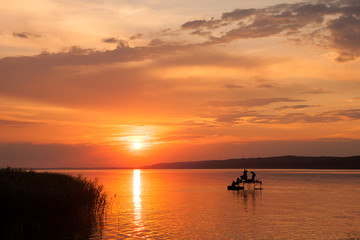 Wall Mural - Beautiful sunset over Lake Balaton with silhouettes of anglers an reed