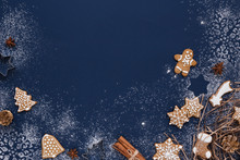 Christmas Background With Gingerbread And Snow On Navy Colored Surface. Holiday Mood Card. Top View, Copy Space.