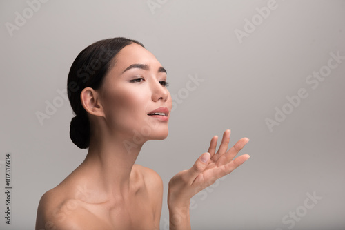 Elegant Beauty Charming Naked Young Asian Girl Is Standing And Holding Her Palm Up While Looking Ahead With Slight Smile And Tenderness Isolated Background And Copy Space In Right Side Stock Photo Elegant Beauty Charming Naked Young Asian Girl Is Standing And Holding Her Palm Up While Looking Ahead With Slight Smile And Tenderness Isolated Background And Copy Space In Right Side Stock Photo