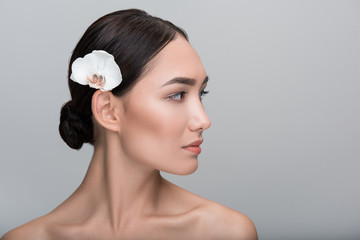 natural beauty style. close-up profile of face of young naked charming asian woman with white orchid