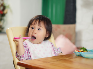 Wall Mural - baby girl eating vegetable at home