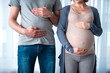 © Yakobchuk Olena - Close up of pregnant woman and her standing and touching their belly. Man is pretending as if he is also pregnant. Empathy concept
