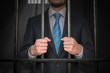 © vchalup - Businessman or politician behind bars in prison cell.