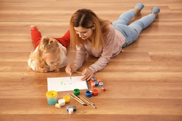 Canvas Print - Mother with cute girl painting picture on sheet of paper, indoors