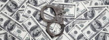 Police Handcuffs Lie On A Lot Of Dollar Bills. The Concept Of Illegal Possession Of Money, Illegal Transactions With US Dollars. Economic Crime