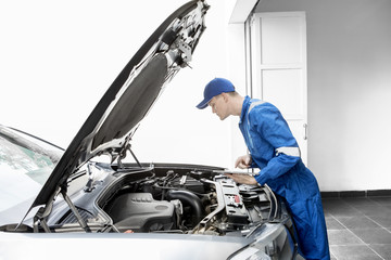 European mechanic examining a car with tablet