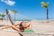 © Maridav - Beach vacation woman happy sleeping in hammock at holiday resort - Caribbean travel holidays Asian girl lying down relaxing outdoors sunbathing.