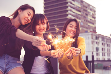 Happy group of asia girl friends enjoy and play sparkler at roof top party at evening sunset,Holiday celebration festive,teenage lifestyle,freedom and fun.