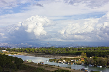 Wall Mural - Landscape with a river and mountains. Large white cumulus clouds and purple clouds.