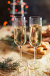 © Olena - glasses with champagne, biscuits, a Christmas tree and New Year's lights on a New Year's festive table