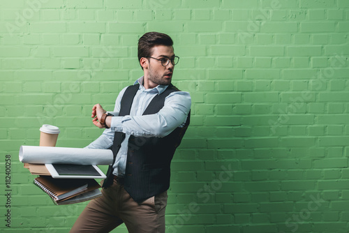 Cuadros en Lienzo young handsome busy businessman with tablet, documents and cup of coffee in fron