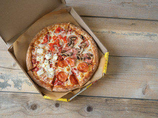 Pizza in delivery box on wooden table