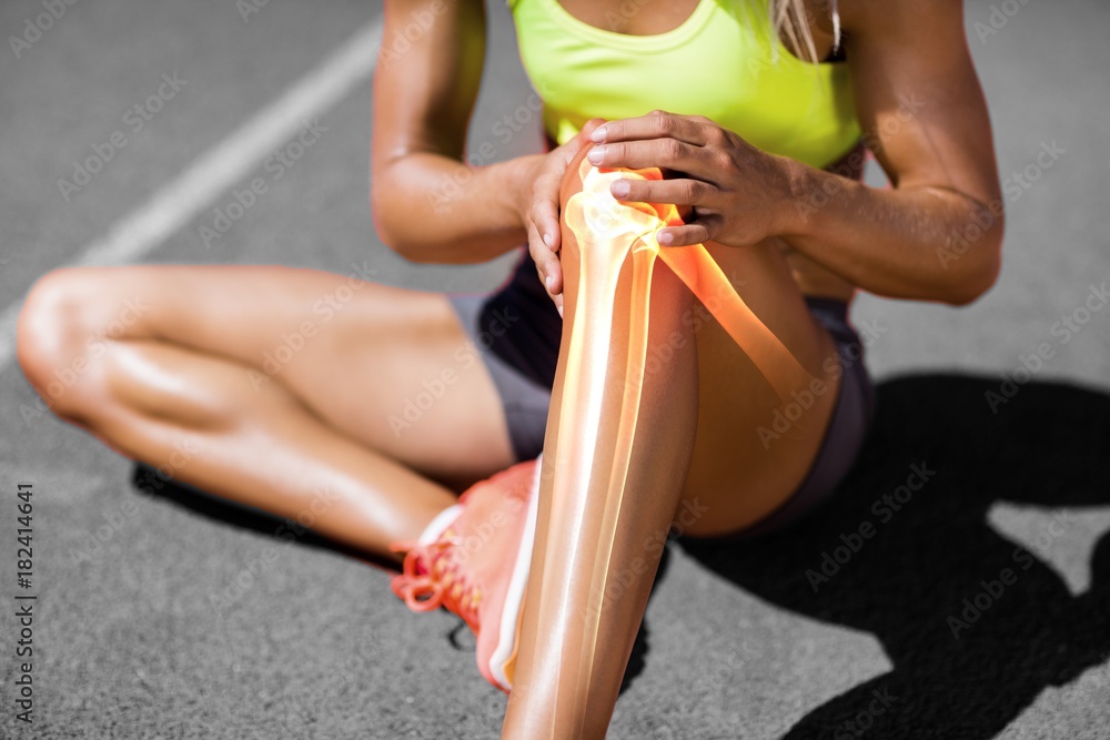 Low section of sportswoman suffering from knee pain - obrazy, fototapety, plakaty 
