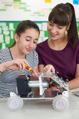 Wall Mural - teacher talking to female pupil studying robotics in science lesson