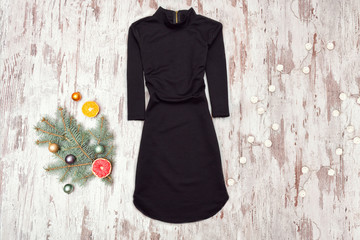 Wall Mural - Little black dress with sleeves and spruce branch on a wooden background. Fashionable concept