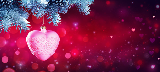 Wall Mural - heart bauble hanging at fir branches in red shiny background