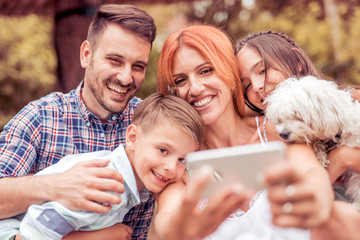 Wall Mural - Happy family smiling at the camera with their dog .