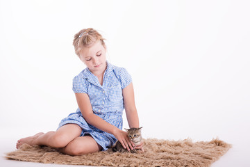 young girl in a studion on white background playing with a kitten