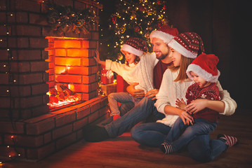 Wall Mural - happy family sitting by fireplace on christmas eve
