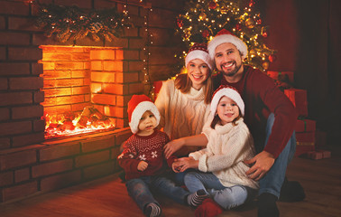 Wall Mural - happy family sitting by fireplace on christmas eve