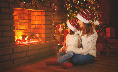 Wall Mural - family mother and child daughter watching fireplace at christmas
