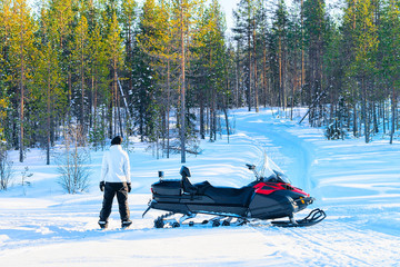 Poster - Woman at snowmobile on frozen lake at winter Rovaniemi