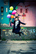 © Alexander - happy young woman jumping high while holding balloons