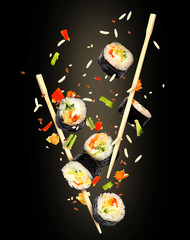 Pieces of sushi frozen in the air on black background