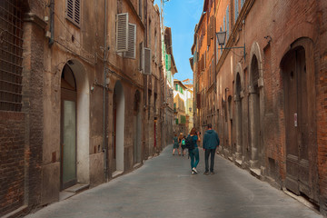 Wall Mural - Beautiful medieval narrow street in the spring, Siena, Italy. Historic centre of Siena has been declared by UNESCO a World Heritage Site.