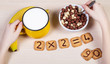 Healthy food for a school children. Milk, banana and funny cookies with numbers. Child has breakfast and does sums using biscuits. Idea of easy arithmetics during eating.