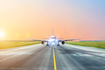 Aircraft taxiing on the runway at the airport at dusk with lights on, view of the nose of the cockpit.