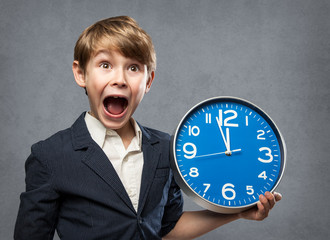 Happy Surprised 7 Year old Boy, Holding a blue Big Clock, just minutes before midnight: either, he is warning us that time is running out, or ready to celebrate New Year