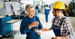 © NDABCREATIVITY - Factory worker discussing data with supervisor in metal factory