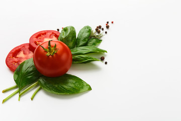 Red tomatoes and basil leaves isolated on white