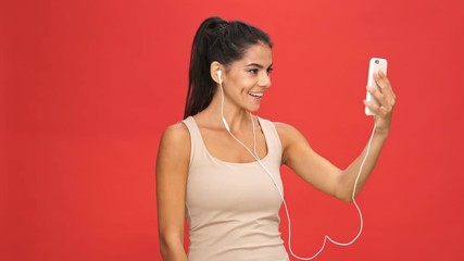 Sticker - Happy brunette woman in singlet talking by video call on smartphone over red background