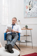 © LIGHTFIELD STUDIOS - Businessman sitting on chair at home and looking at tablet