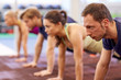 © Syda Productions - group of people doing straight arm plank in gym