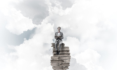 Young businessman or student floating in blue sky and studying t